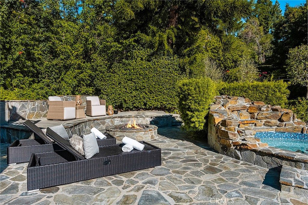 Stone patio with firepit, lounge daybed, and pool reflections